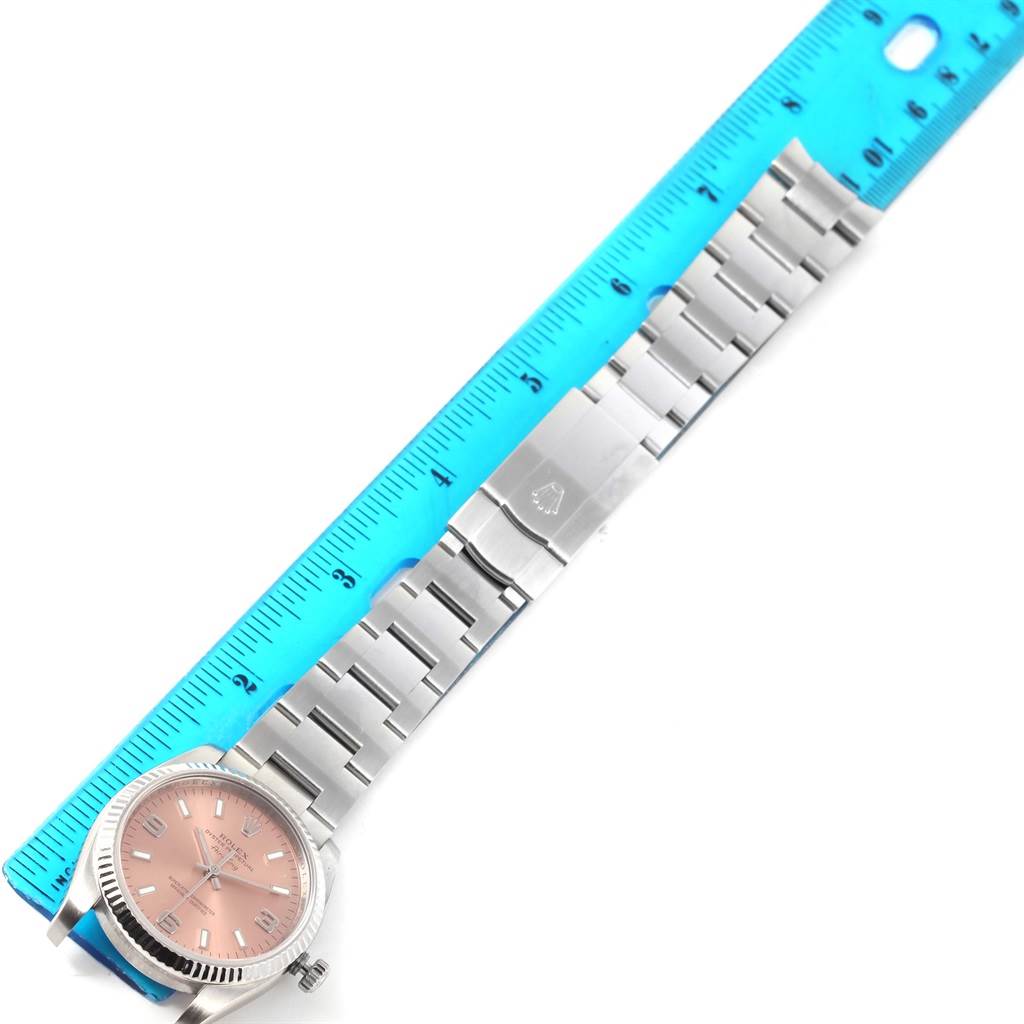 This image shows a Rolex Air-King 114234 Men's Stainless Steel Pink Dial 114234 Men's Stainless Steel Pink Dial watch lying flat, highlighting the face, bezel, and entire metal bracelet next to a blue ruler.