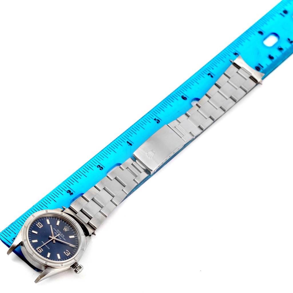 The Rolex Air-King 14010 Men's Stainless Steel Blue Dial 14010 Men's Stainless Steel Blue Dial watch is photographed face-up with its metal bracelet extended alongside a blue ruler.