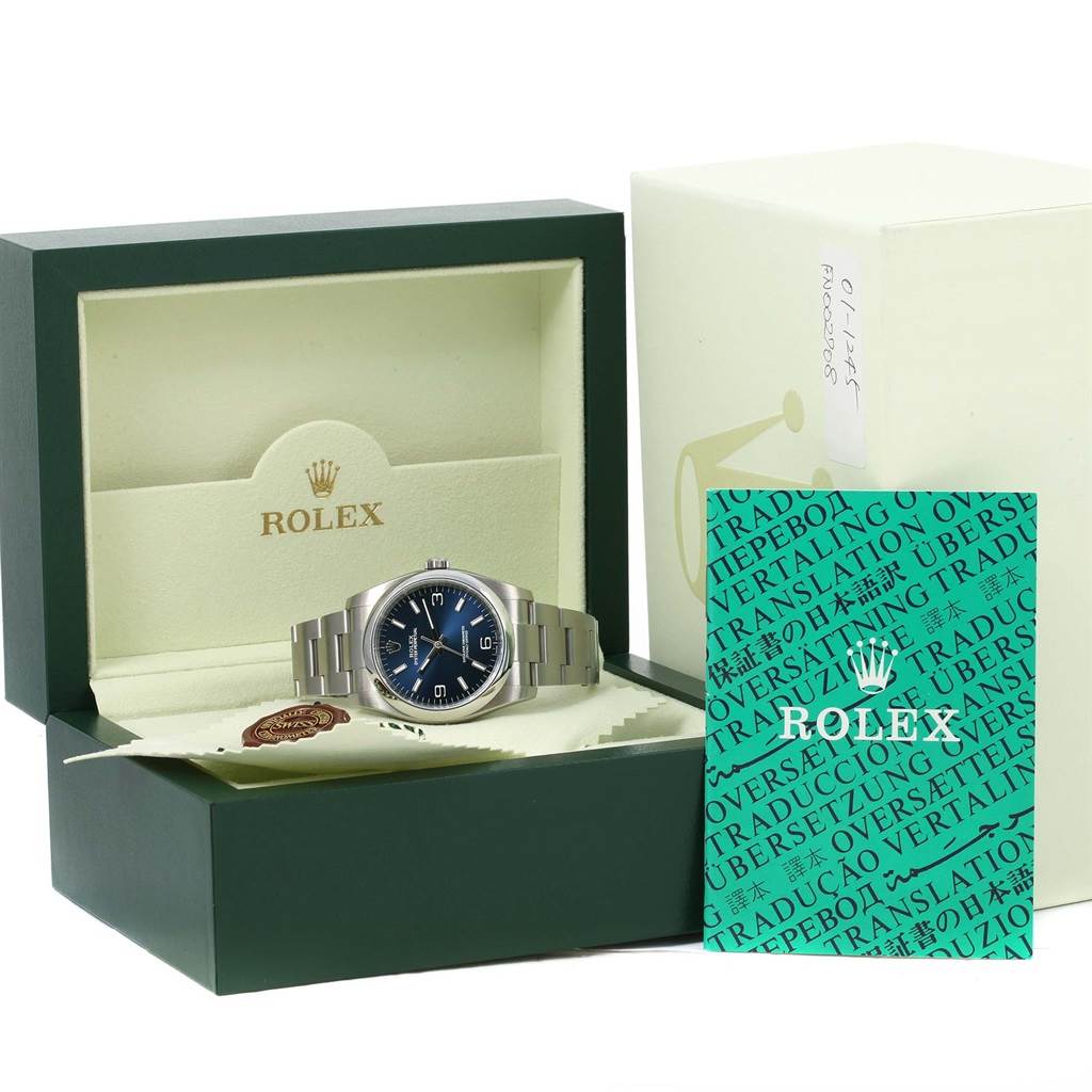 The image shows a Rolex Air-King 116000 Men's Stainless Steel Blue Dial 116000 Men's Stainless Steel Blue Dial watch in its original open box with booklets and accessories.