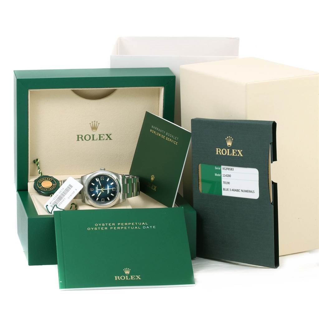 The image shows a Rolex Air-King 114200BLASO Men's Stainless Steel Blue Dial 114200BLASO Men's Stainless Steel Blue Dial watch with its box, warranty booklet, tag, and authenticity card.