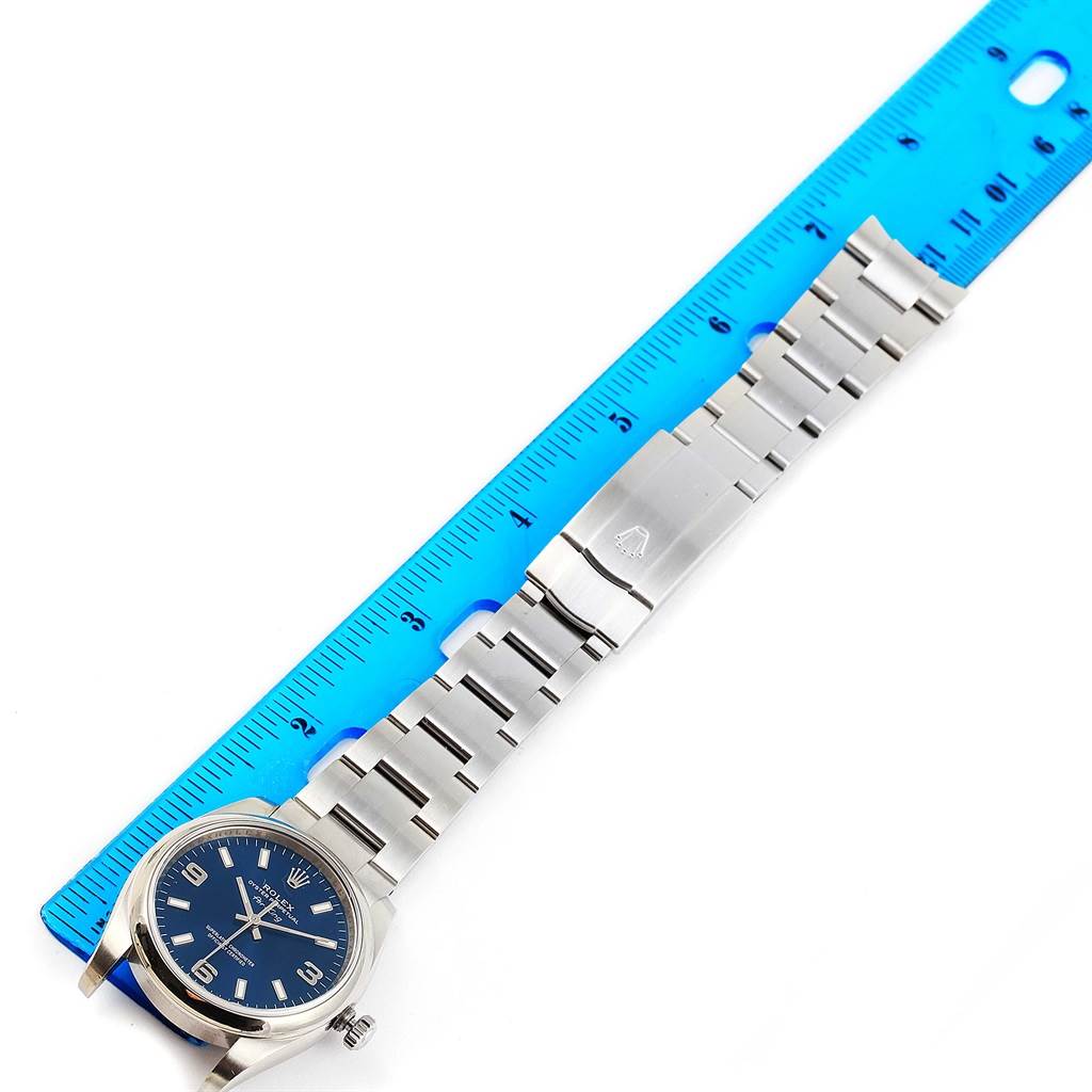 Top-down view of a Rolex Air-King 114200 Men's Stainless Steel Blue Dial 114200 Men's Stainless Steel Blue Dial watch, showing the face, band, clasp, and a measuring ruler.