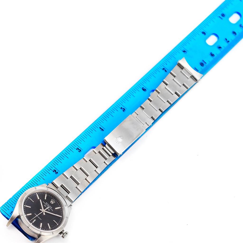 The image shows a full view of the Rolex Air-King 14010 Men's Stainless Steel Black Dial 14010 Men's Stainless Steel Black Dial watch laid flat next to a blue ruler.