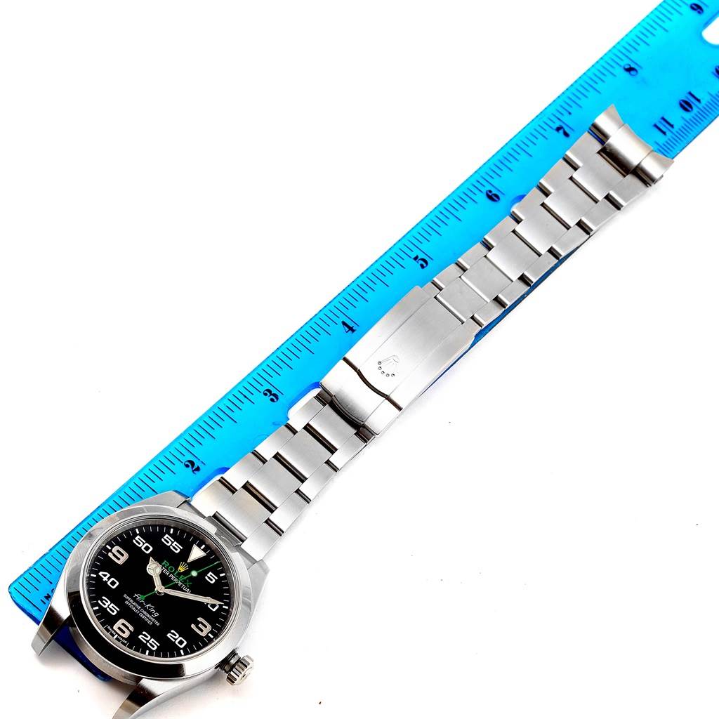 The Rolex Air-King 116900 Men's Stainless Steel Black Dial 116900 Men's Stainless Steel Black Dial watch is shown from an overhead angle, displaying its face, bracelet, and clasp alongside a ruler.