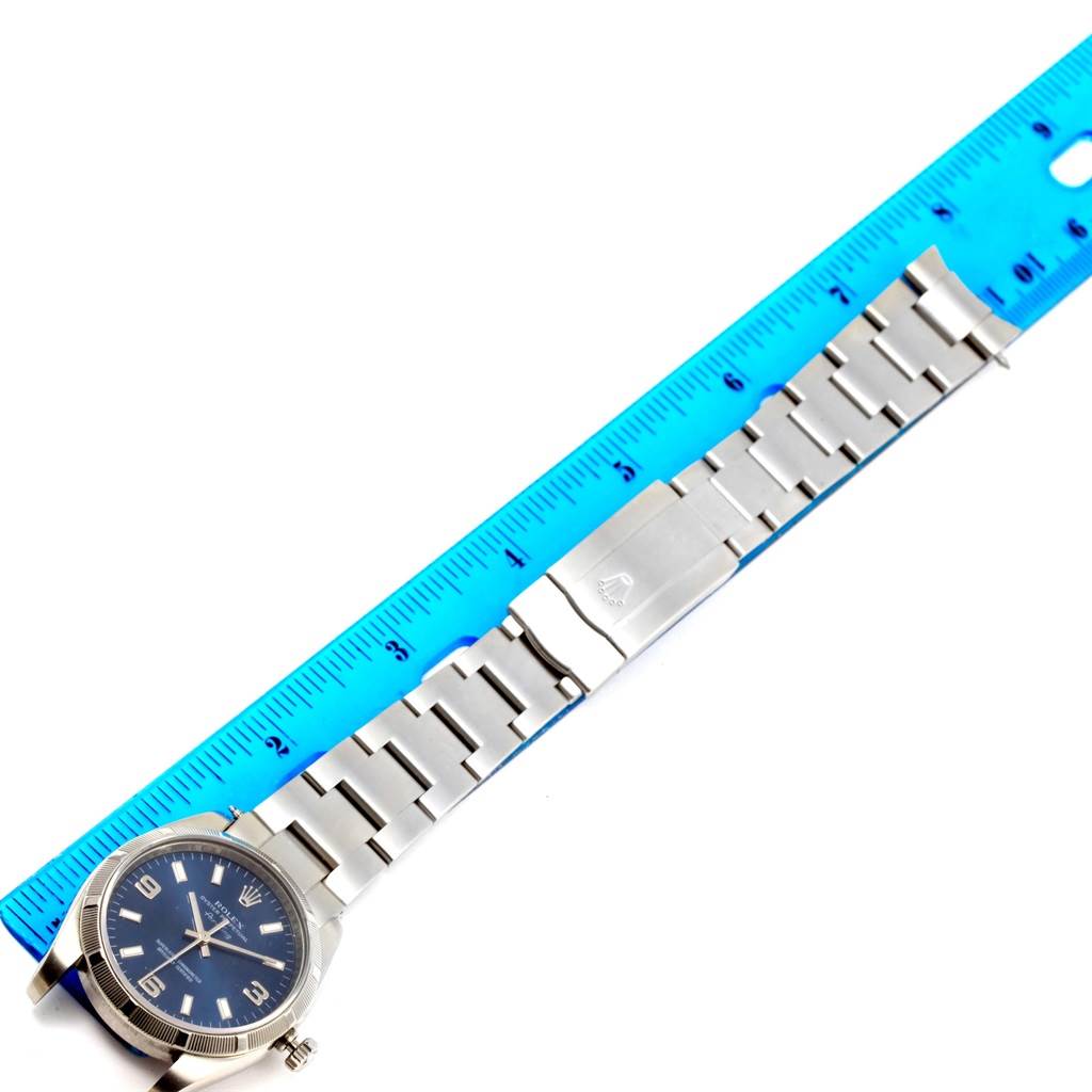 The image shows a Rolex Air-King 114210 Men's Stainless Steel Blue Dial 114210 Men's Stainless Steel Blue Dial watch laid flat, with a blue ruler for size reference; it displays the watch face, bracelet, and clasp.