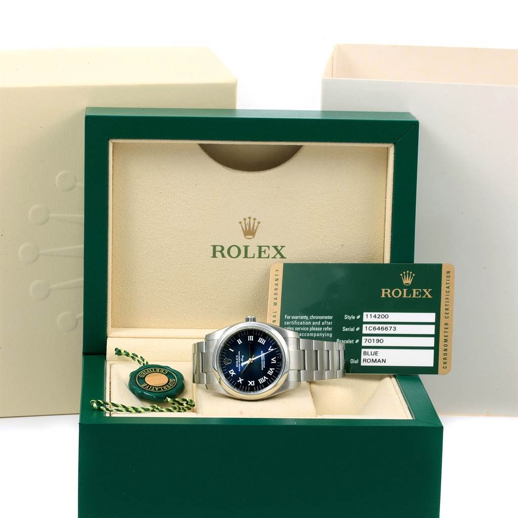 The image shows a Rolex Air-King 114200 Men's Stainless Steel Blue Dial 114200 Men's Stainless Steel Blue Dial watch in an open box, revealing the watch, warranty card, and a green tag.