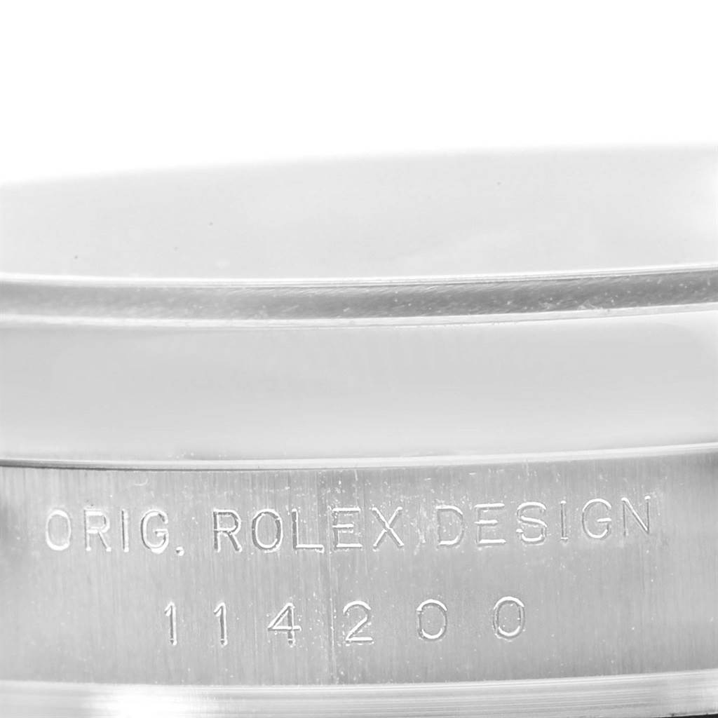 The image shows a close-up of the engraved side of a Rolex Air-King 114200 Men's Stainless Steel Blue Dial 114200 Men's Stainless Steel Blue Dial model 114200, highlighting the text "ORIG. ROLEX DESIGN."