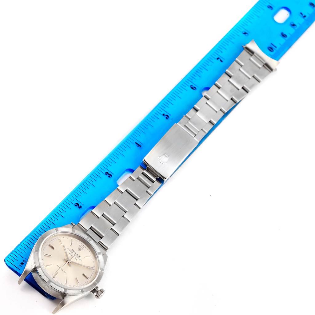 The image shows a Rolex Air-King 14010 Men's Stainless Steel Silver Dial 14010 Men's Stainless Steel Silver Dial watch placed next to a blue ruler, highlighting the bracelet and face.