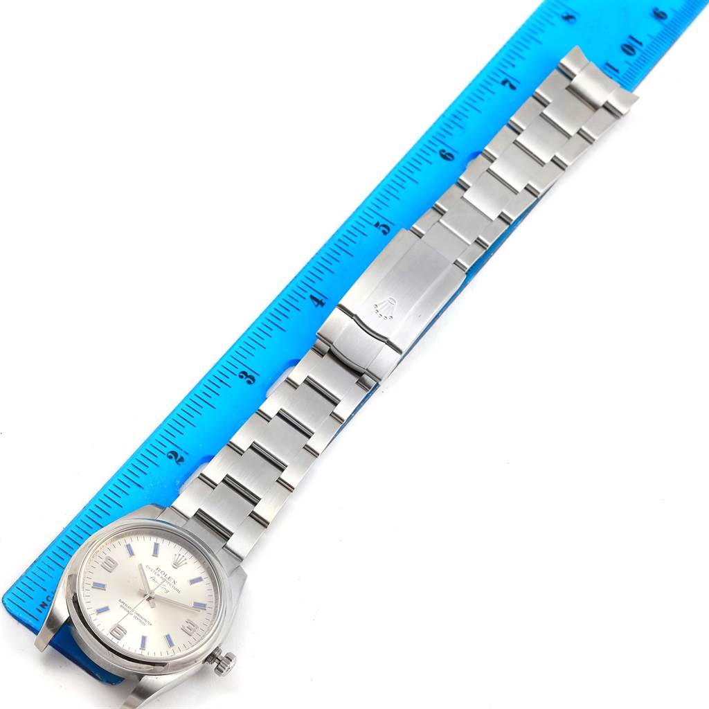 The image shows a Rolex Air-King 114200 Men's Stainless Steel Silver Dial 114200 Men's Stainless Steel Silver Dial watch laid flat next to a ruler, highlighting the watch band and clasp.