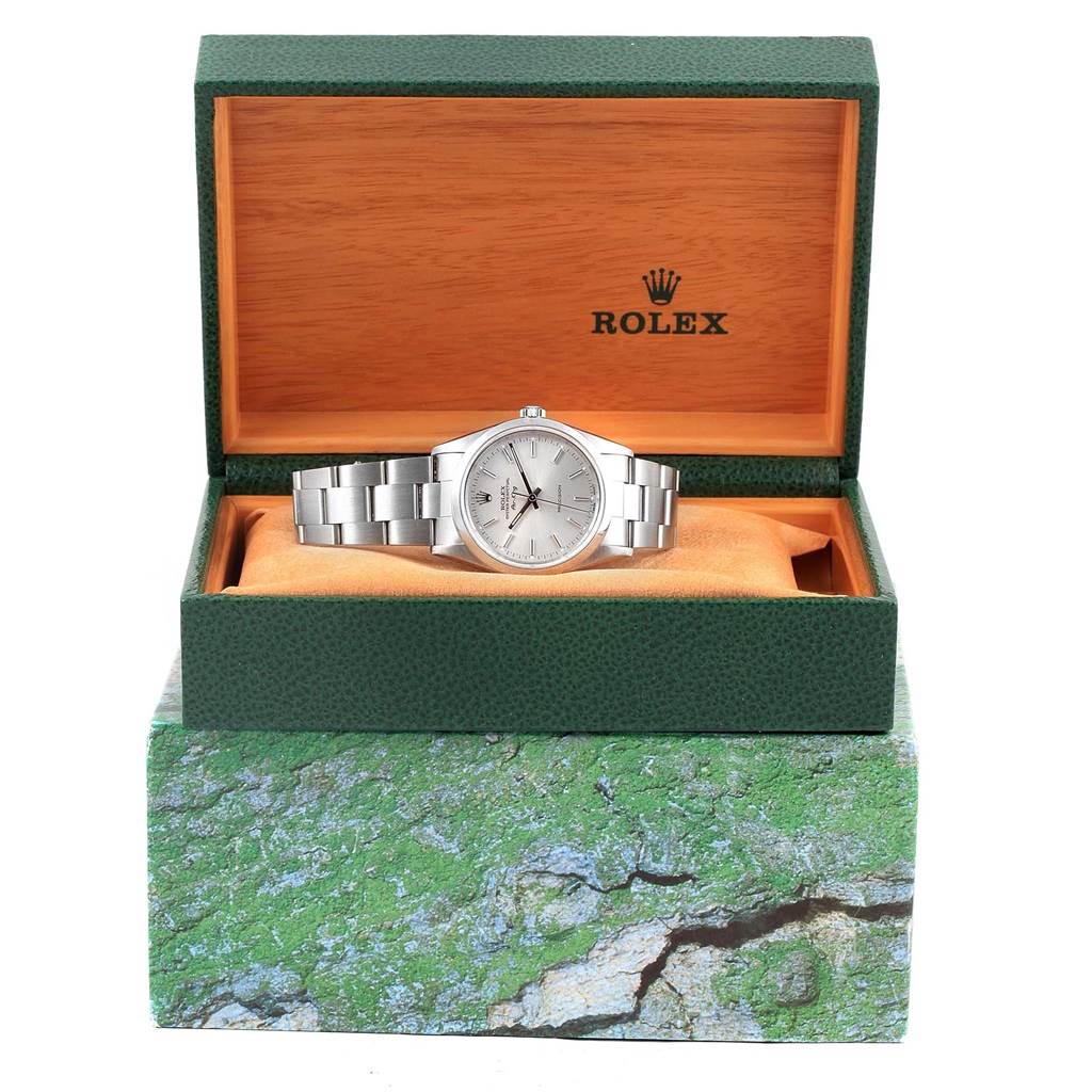 The Rolex Air-King 14000 Men's Stainless Steel Silver Dial 14000 Men's Stainless Steel Silver Dial watch is displayed frontally, resting in an open, green and orange, textured box.