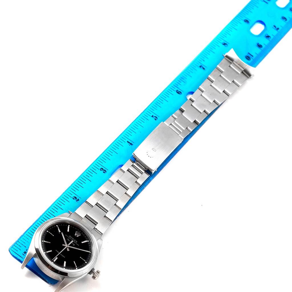 The Rolex Air-King 14000 Men's Stainless Steel Black Dial 14000 Men's Stainless Steel Black Dial watch is laid flat alongside a ruler, showing the face, bracelet, and clasp from a top-down angle.