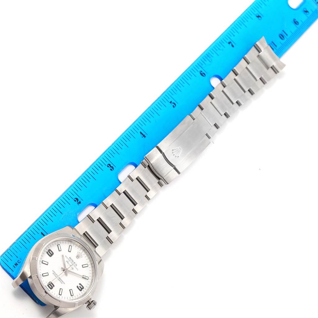 A Rolex Air-King 114210 Men's Stainless Steel White Dial 114210 Men's Stainless Steel White Dial watch is shown laid flat, displaying the face, bracelet, clasp, and partial ruler for size reference.