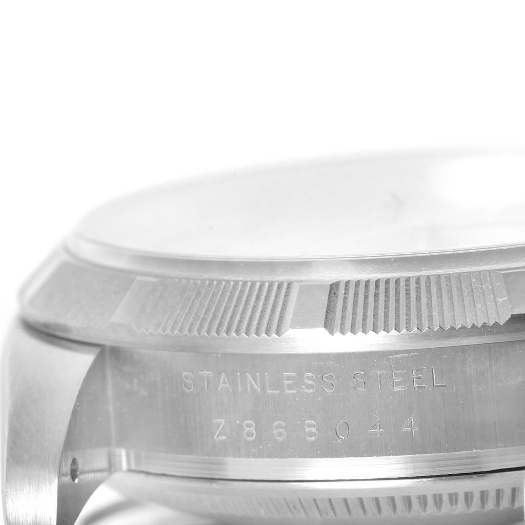 This image shows a close-up of the case and part of the bezel of a Rolex Air-King 114210 Men's Stainless Steel White Dial 114210 Men's Stainless Steel White Dial watch, revealing its stainless steel composition and serial number.
