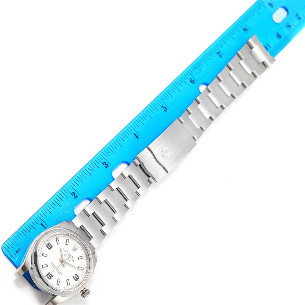 The Rolex Air-King 114200 Men's Stainless Steel White Dial 114200 Men's Stainless Steel White Dial watch is shown lying flat, with the strap and clasp extended alongside a ruler for scale.