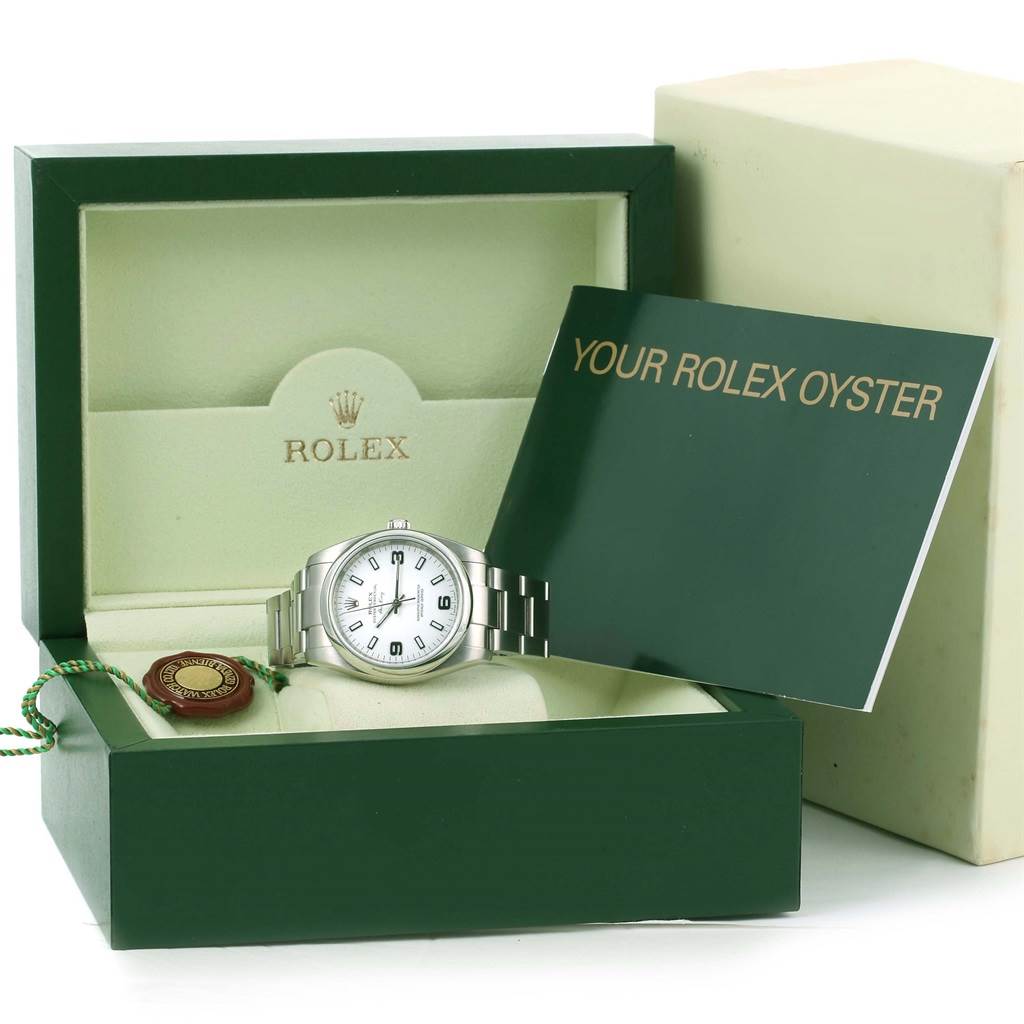 The Rolex Air-King 114200 Men's Stainless Steel White Dial 114200 Men's Stainless Steel White Dial watch is displayed in its open box alongside a booklet and a tag.