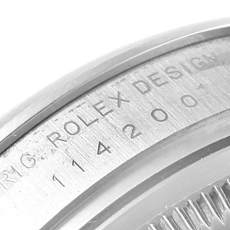 The image shows a close-up of the serial number and "ROLEX DESIGN" engraving on the case of a Rolex Air-King 114200 Stainless Steel Blue Dial 114200 Stainless Steel Blue Dial watch.