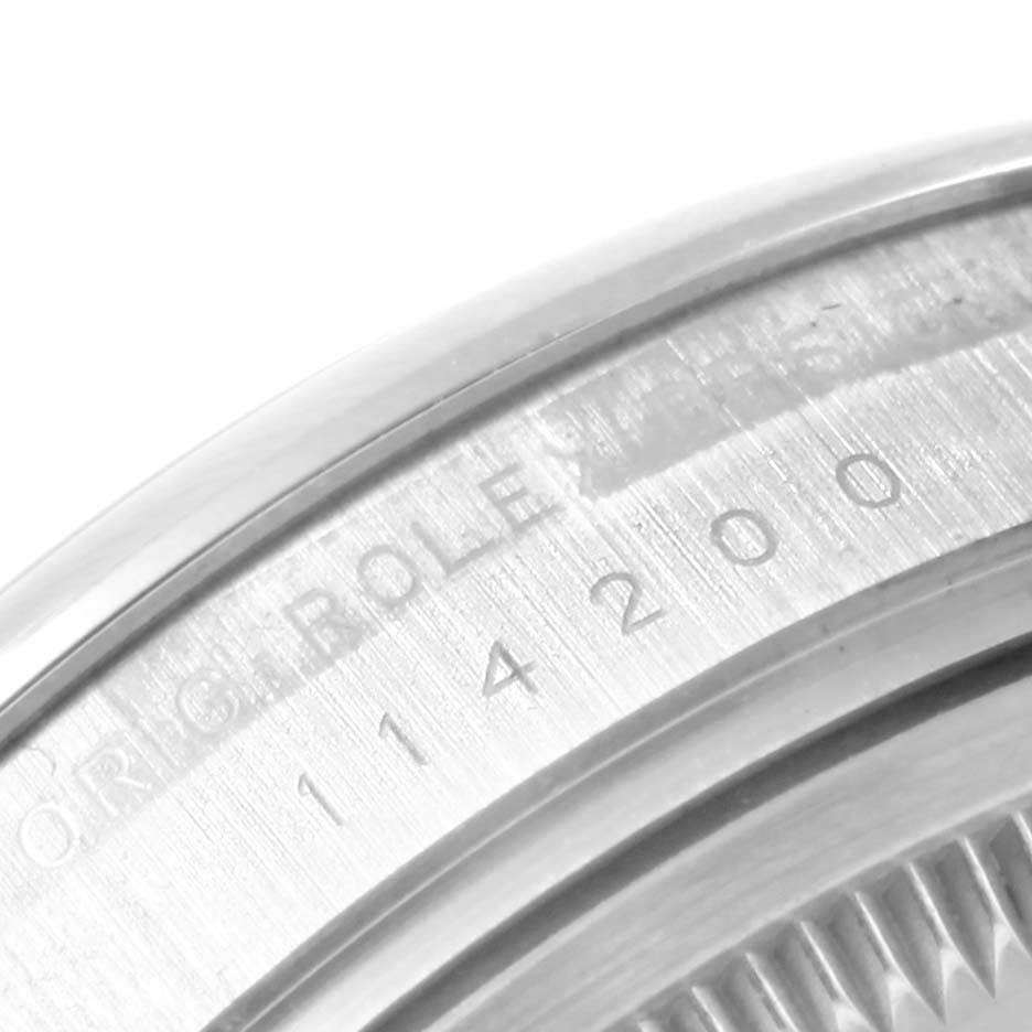 The image shows a close-up of the serial number engravings on the case back of a Rolex Air-King 114200 Men's Stainless Steel Silver Dial 114200 Men's Stainless Steel Silver Dial watch.