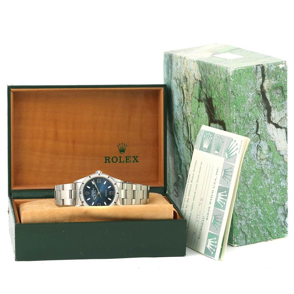 The image shows a Rolex Air-King 14010 Men's Stainless Steel Blue Dial 14010 Men's Stainless Steel Blue Dial watch placed inside its open box along with an instruction booklet on the side.