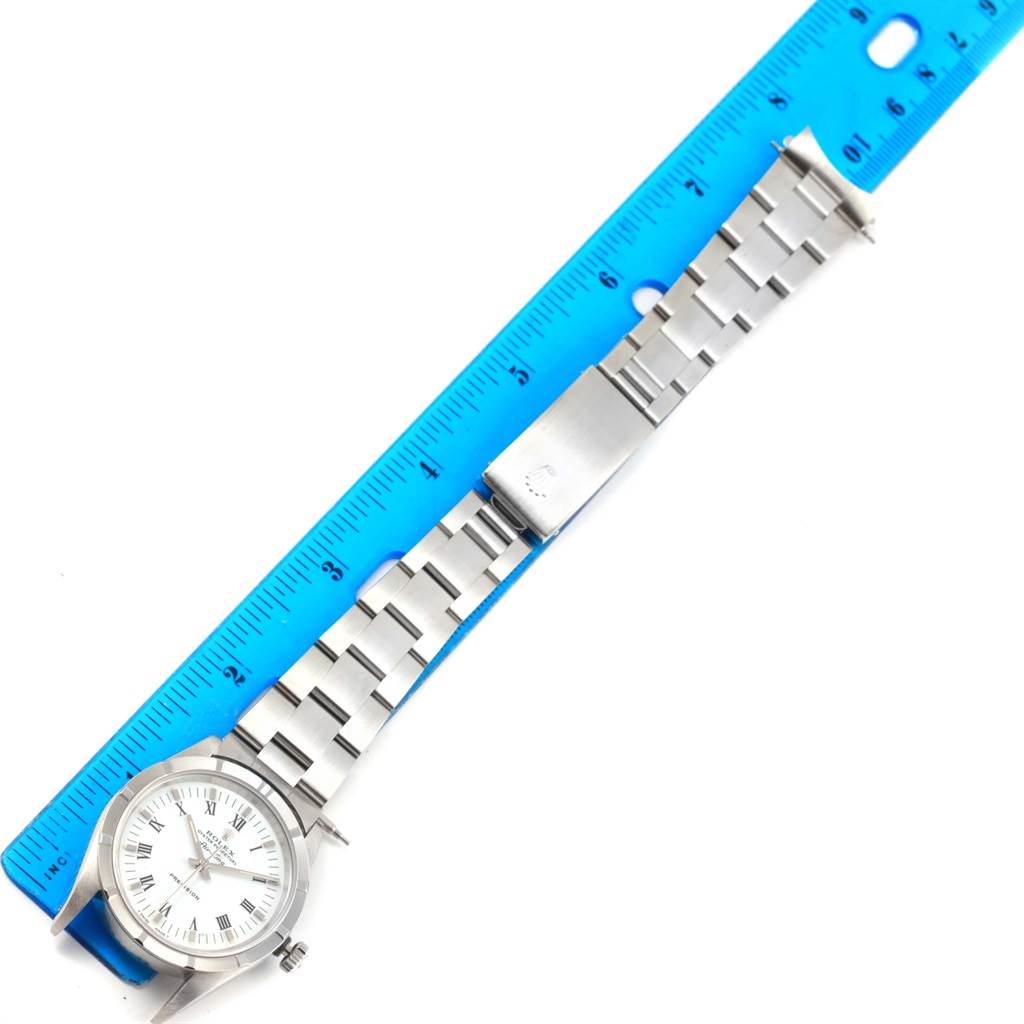 The Rolex Air-King 14010 Men's Stainless Steel White Dial 14010 Men's Stainless Steel White Dial watch is shown from a top-down angle, displaying the face and metal band placed next to a blue ruler.