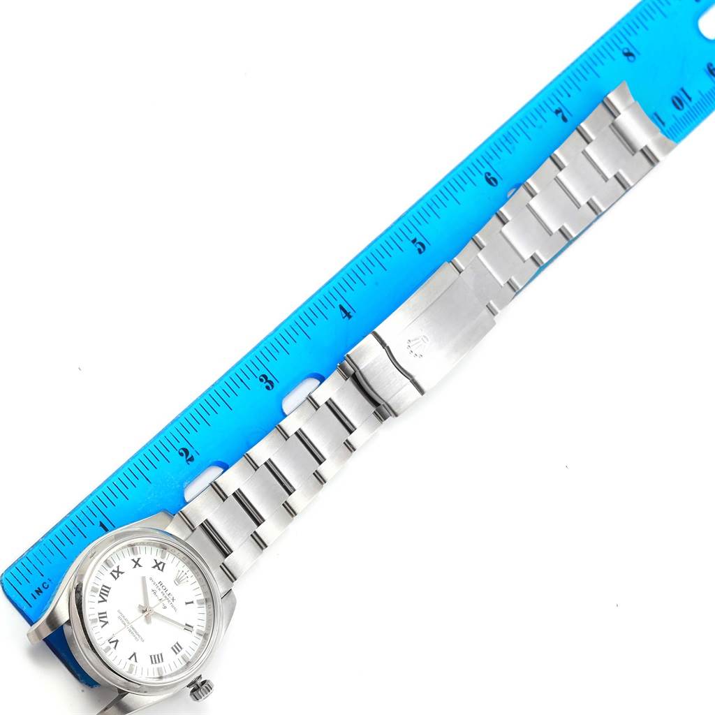 The Rolex Air-King 114200 Men's Stainless Steel White Dial 114200 Men's Stainless Steel White Dial watch is displayed laying flat, showing its dial, case, bracelet, and clasp, next to a ruler for scale.