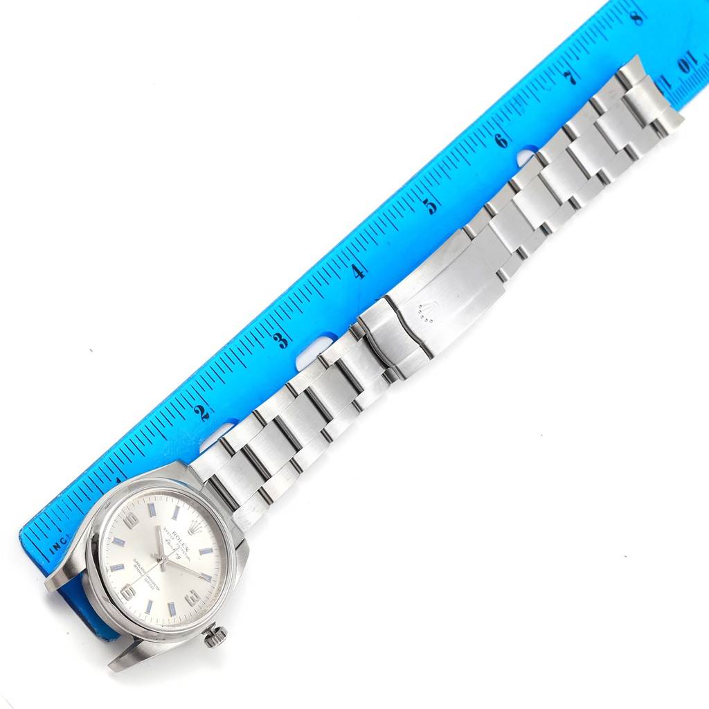 The image shows a Rolex Air-King 114200 Stainless Steel Silver Dial 114200 Stainless Steel Silver Dial watch laid flat, measured against a blue ruler, displaying the face, band, and clasp.