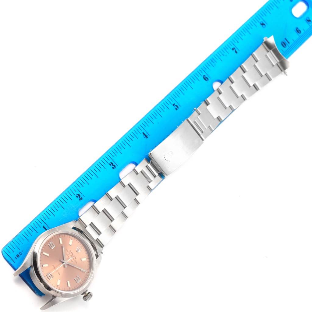 The image shows a horizontal view of a Rolex Air-King 14000 Stainless Steel Pink Dial 14000 Stainless Steel Pink Dial watch with its bracelet spread out alongside a blue ruler.