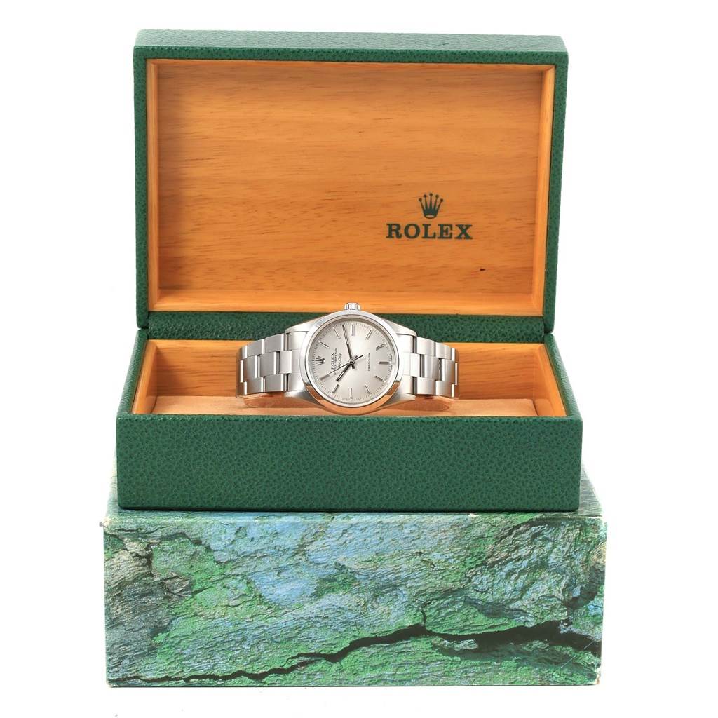 The Rolex Air-King 14000 Men's Stainless Steel Silver Dial 14000 Men's Stainless Steel Silver Dial watch is displayed front-facing in its open green and wooden box, sitting atop a green textured base.