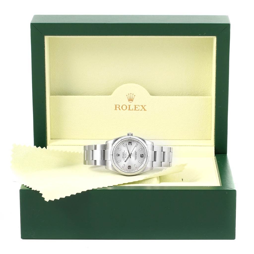 The Rolex Air-King 114210 Stainless Steel Silver Dial 114210 Stainless Steel Silver Dial watch is shown from the front inside its green and beige branded case with a cleaning cloth.