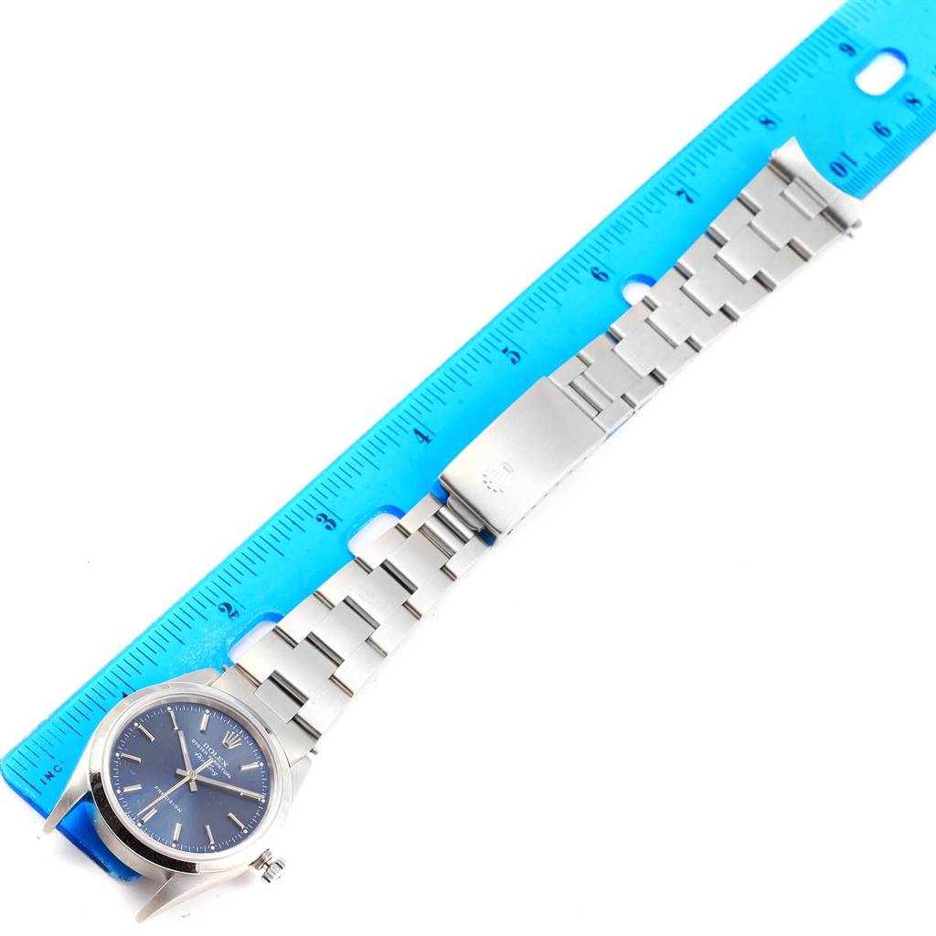 The image shows a top-down view of a Rolex Air-King 14000 Men's Stainless Steel Blue Dial 14000 Men's Stainless Steel Blue Dial watch, including its face, bracelet, and clasp, alongside a blue ruler.