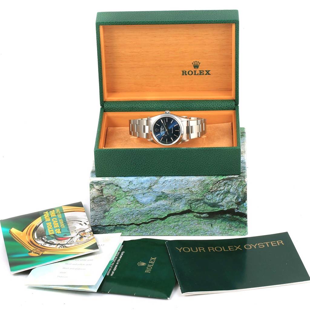The photo shows a Rolex Air-King 14000 Men's Stainless Steel Blue Dial 14000 Men's Stainless Steel Blue Dial watch in its green case, alongside booklets and manuals.