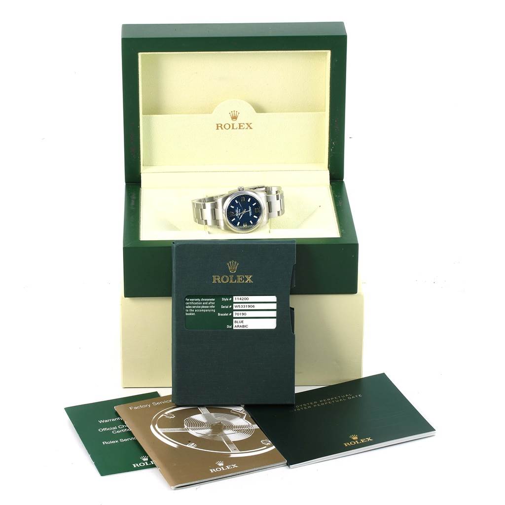 The image shows the Rolex Air-King 114200 Men's Stainless Steel Blue Dial 114200 Men's Stainless Steel Blue Dial watch at a slight angle in its opened box, accompanied by booklets and warranty card.