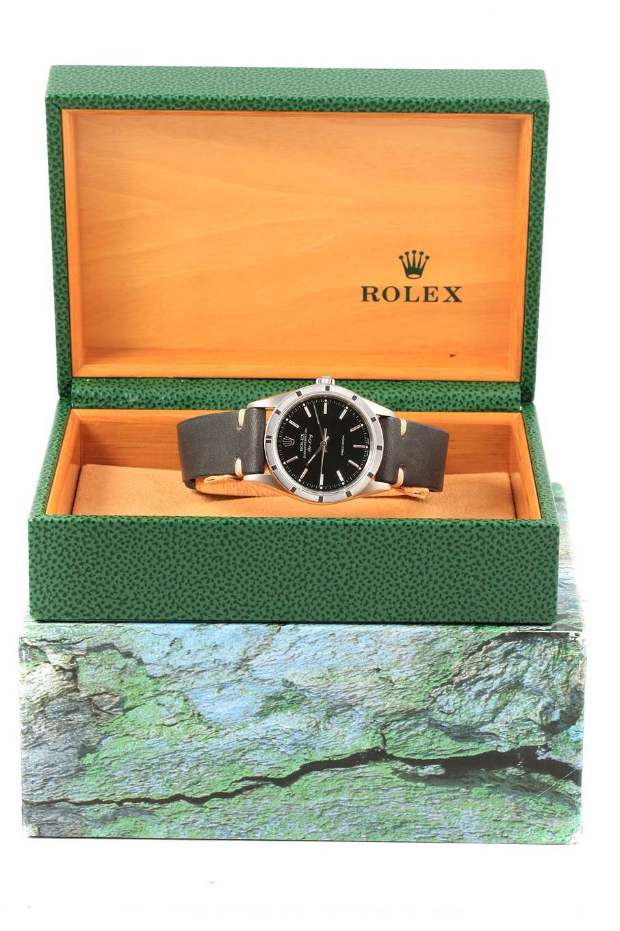 The Rolex Air-King 14010 Men's Stainless Steel Black Dial 14010 Men's Stainless Steel Black Dial watch is shown inside an open green and wooden Rolex case, viewed from the front.