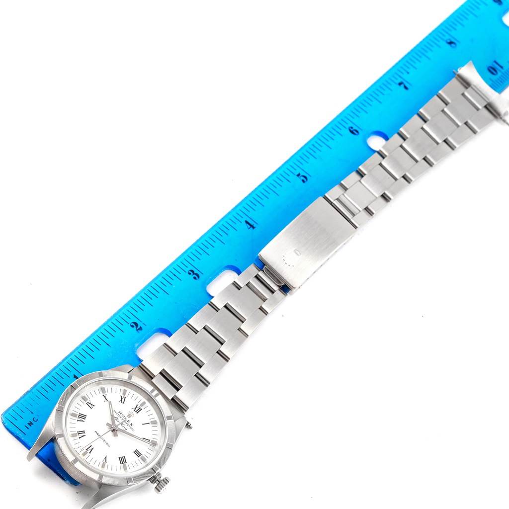 The Rolex Air-King 14010 Men's Stainless Steel White Dial 14010 Men's Stainless Steel White Dial watch is shown flat, along with its stainless steel bracelet next to a blue ruler.