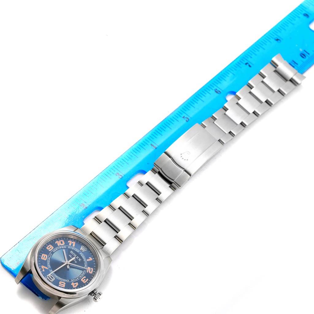 The image shows a top view of a Rolex Air-King 114200 Men's Stainless Steel Blue Dial 114200 Men's Stainless Steel Blue Dial watch, highlighting its face, bracelet, and clasp alongside a measuring ruler.