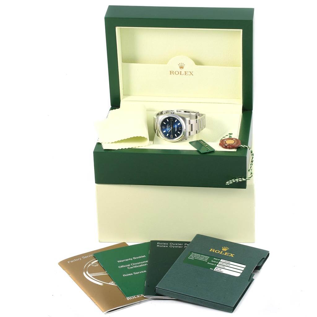 The Rolex Air-King 114200 Men's Stainless Steel Blue Dial 114200 Men's Stainless Steel Blue Dial watch is displayed in its open box along with booklets and accessories.