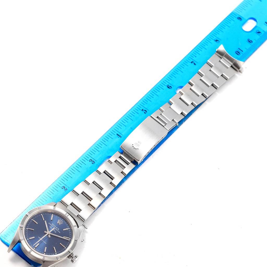 The image shows a top-down angle of a Rolex Air-King 14010 Men's Stainless Steel Blue Dial 14010 Men's Stainless Steel Blue Dial watch with a blue dial, stainless steel bracelet, and a blue ruler for measurement.