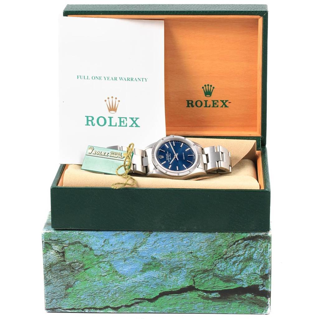 The Rolex Air-King 14010 Men's Stainless Steel Blue Dial 14010 Men's Stainless Steel Blue Dial watch is shown at eye level in an open box, alongside warranty papers and a tag.