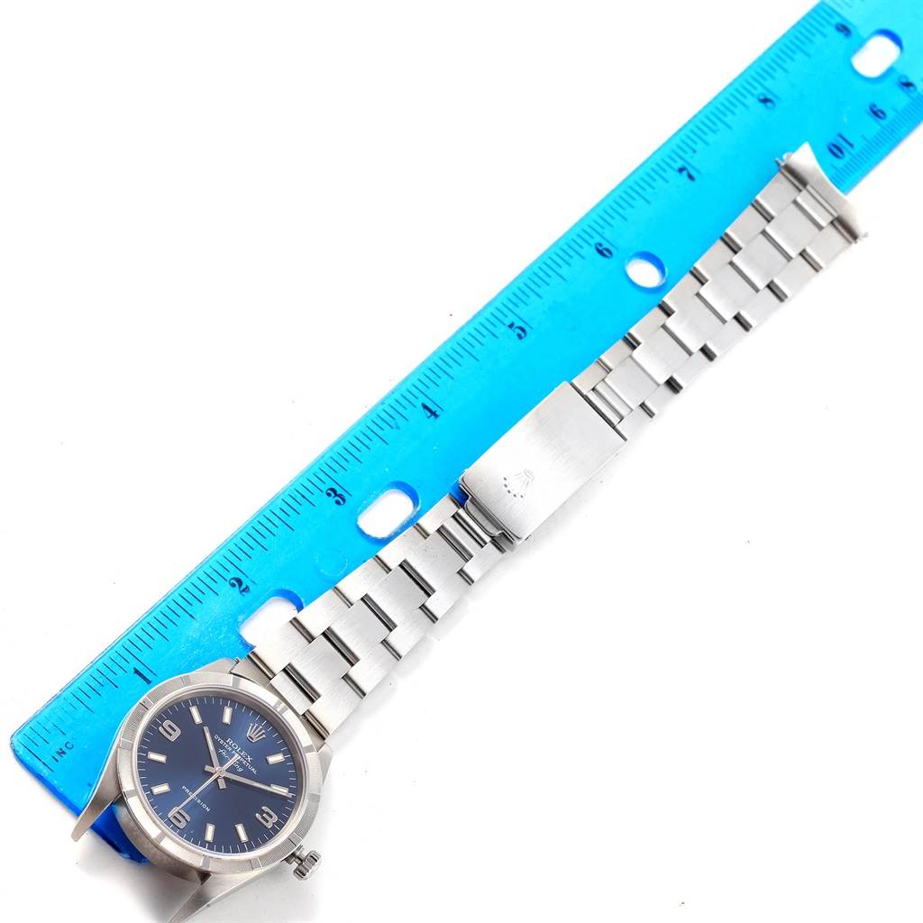 A Rolex Air-King 14010 Men's Stainless Steel Blue Dial 14010 Men's Stainless Steel Blue Dial watch is shown laid flat with its face, bracelet, and clasp visible, next to a blue ruler for scale.