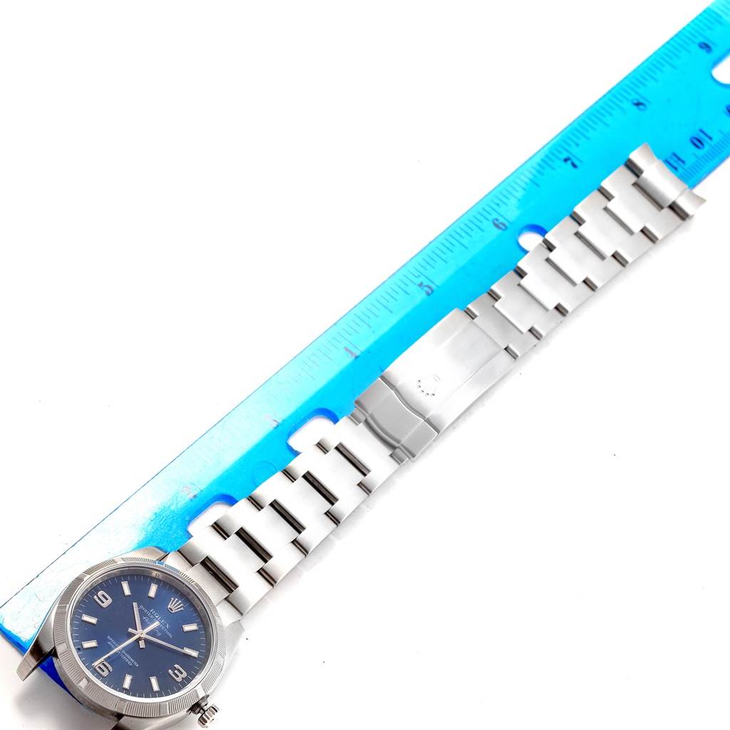 The image shows a Rolex Air-King 114210 Men's Stainless Steel Blue Dial 114210 Men's Stainless Steel Blue Dial watch laid flat next to a blue ruler, displaying the dial, bracelet, and clasp.