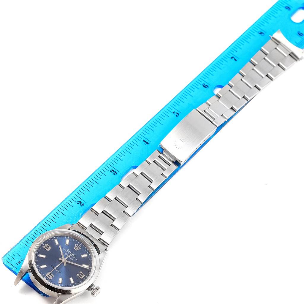 The Rolex Air-King A643381 Men's Stainless Steel Blue Dial A643381 Men's Stainless Steel Blue Dial watch is shown from a top-down angle, with the face, band, and clasp visible next to a ruler.