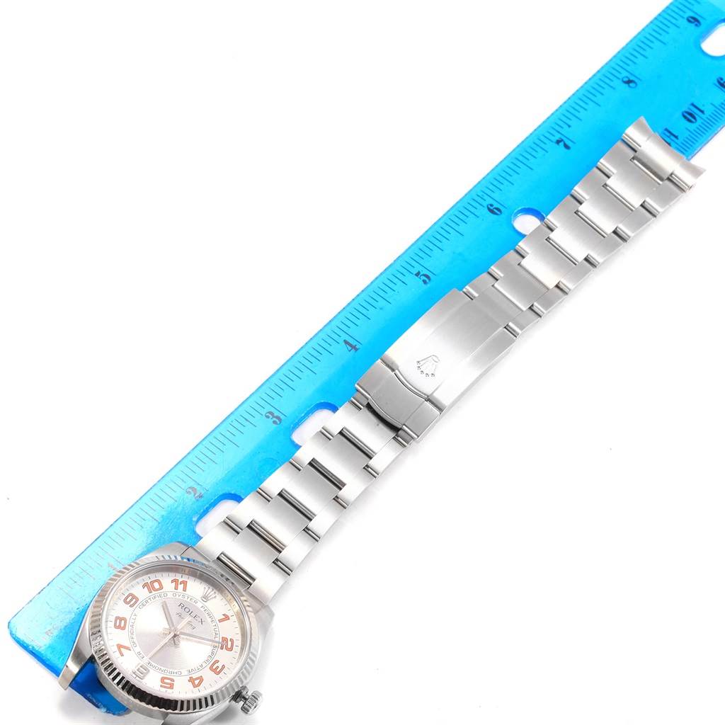 The image shows a Rolex Air-King 114234 Men's Stainless Steel Silver Dial 114234 Men's Stainless Steel Silver Dial watch laid flat beside a blue ruler, displaying its face, bracelet, and clasp.