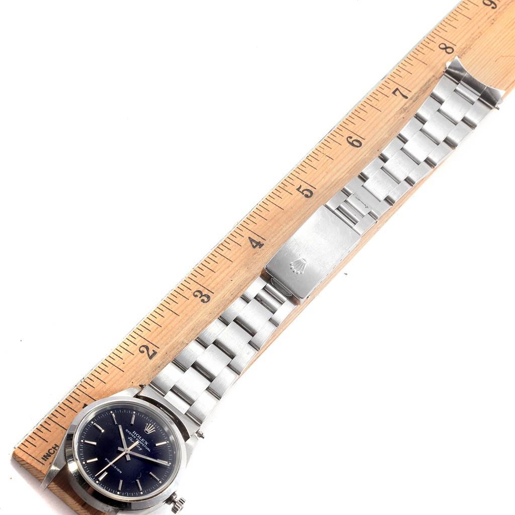 The Rolex Air-King 14000 Men's Stainless Steel Black Dial 14000 Men's Stainless Steel Black Dial watch is shown from a top-down angle, displaying its face, stainless steel bracelet, and clasp alongside a ruler for scale.