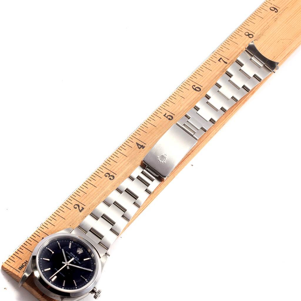 This image shows a Rolex Air-King 14000 Men's Stainless Steel Black Dial 14000 Men's Stainless Steel Black Dial watch laid flat next to a ruler, highlighting its bracelet and clasp.
