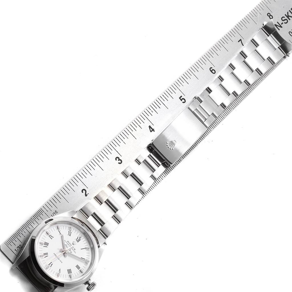 The Rolex Air-King 14000 Men's Stainless Steel White Dial 14000 Men's Stainless Steel White Dial watch is shown from a top-down angle, highlighting its face, bracelet, and clasp next to a ruler.