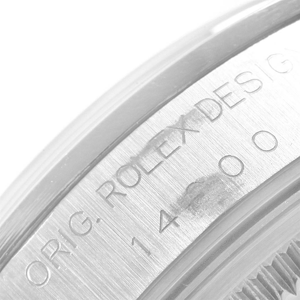 This image shows a close-up angle of the side of a Rolex Air-King 14000 Men's Stainless Steel White Dial 14000 Men's Stainless Steel White Dial watch with engraved text and part of the bezel visible.