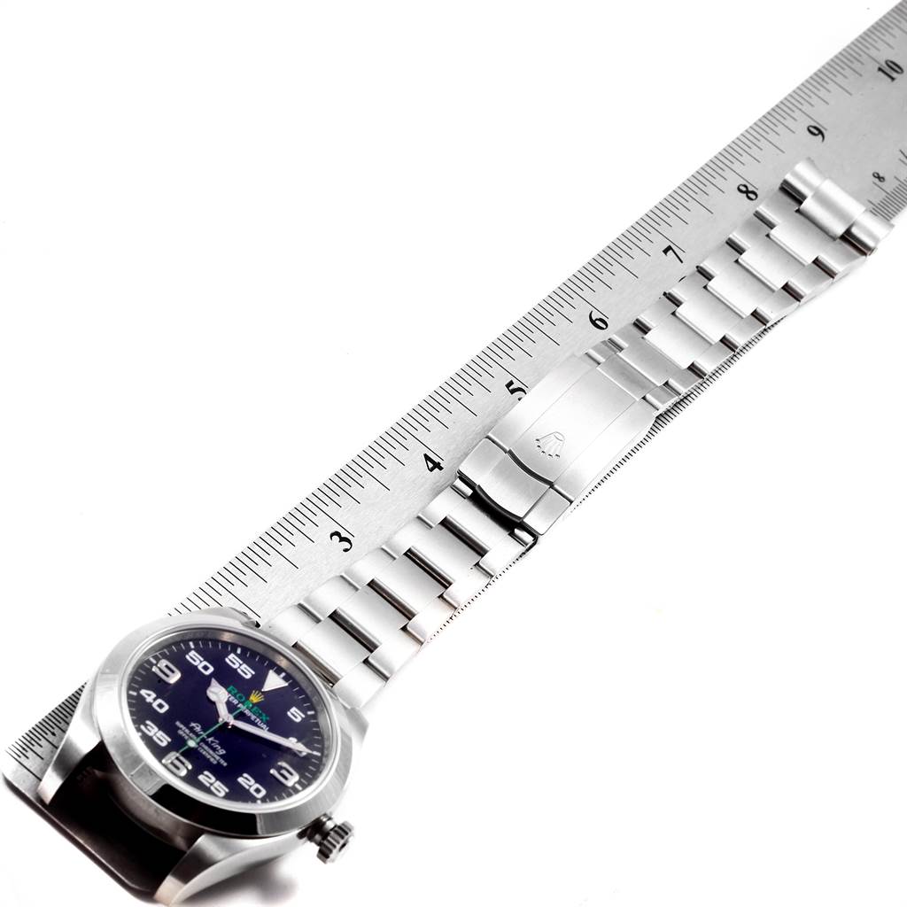 The image shows a side view of a Rolex Air-King 116900 Men's Stainless Steel Black Dial 116900 Men's Stainless Steel Black Dial watch and its metal bracelet on a ruler, measuring its length.