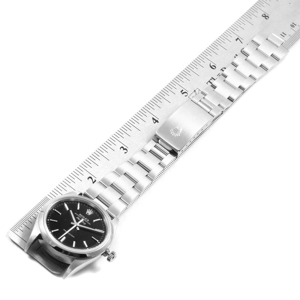 The Rolex Air-King 14000 Men's Stainless Steel Black Dial 14000 Men's Stainless Steel Black Dial watch is displayed from an overhead angle, showing the face, bracelet, and clasp placed alongside a ruler.