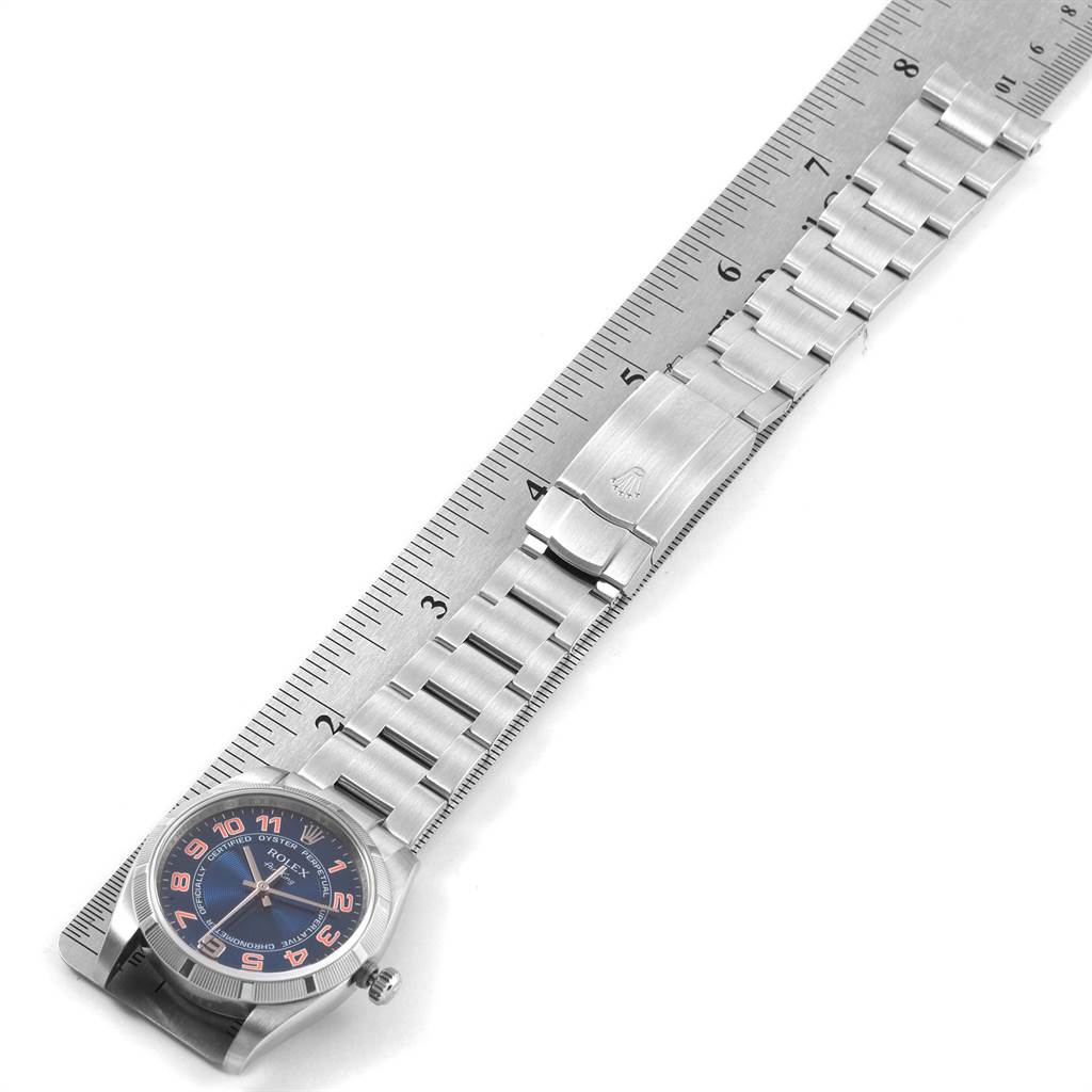 This top-view image shows the Rolex Air-King 114210 Men's Stainless Steel Blue Dial 114210 Men's Stainless Steel Blue Dial watch, complete with a stainless steel bracelet, beside a ruler for size reference.