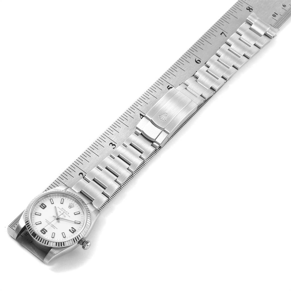 The image shows a top view of a Rolex Air-King 114234 Men's Stainless Steel White Dial 114234 Men's Stainless Steel White Dial watch with its full stainless steel bracelet and clasp aligned with a ruler.