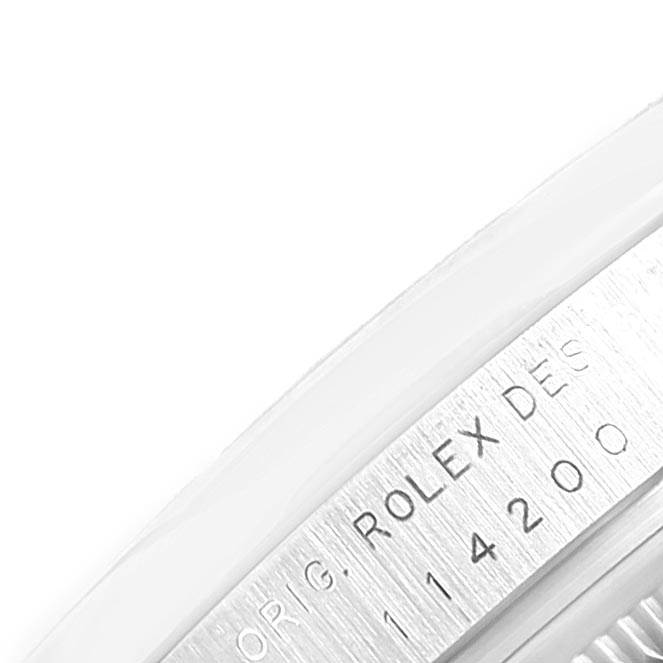 This image shows a close-up angle of the side engraving on the Rolex Air-King 114200 Men's Stainless Steel Silver Dial 114200 Men's Stainless Steel Silver Dial watch, displaying part of the model number and "ROLEX DESIG."