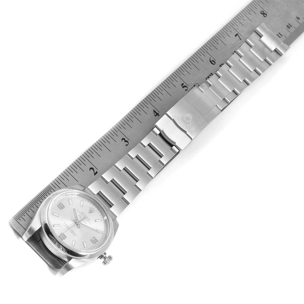 The Rolex Air-King 114200 Men's Stainless Steel Silver Dial 114200 Men's Stainless Steel Silver Dial watch is shown from a top-down angle, displaying the full face, metal strap, clasp, and crown, alongside a ruler for scale.